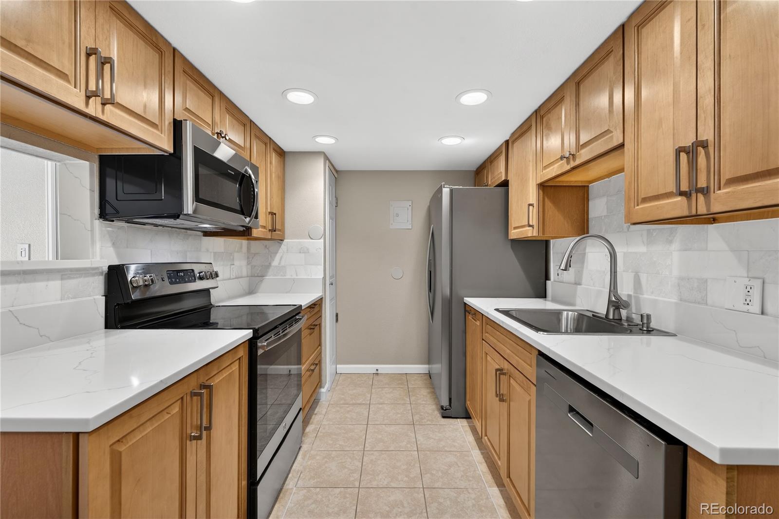 4400 South Quebec Street, Unit 101P Denver, CO 80237 - Photo 7 of 26 a kitchen with stainless steel appliances granite countertop a sink a stove top oven a refrigerator with grey cabinets