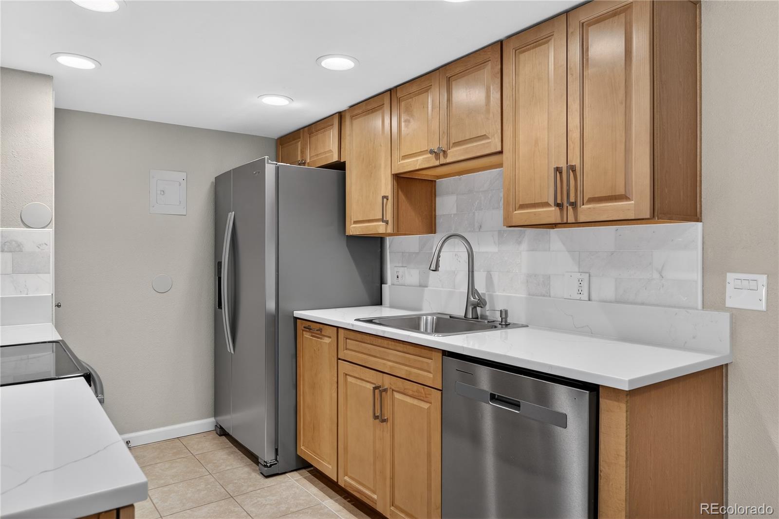 4400 South Quebec Street, Unit 101P Denver, CO 80237 - Photo 8 of 26 a kitchen with stainless steel appliances granite countertop a refrigerator sink and cabinets