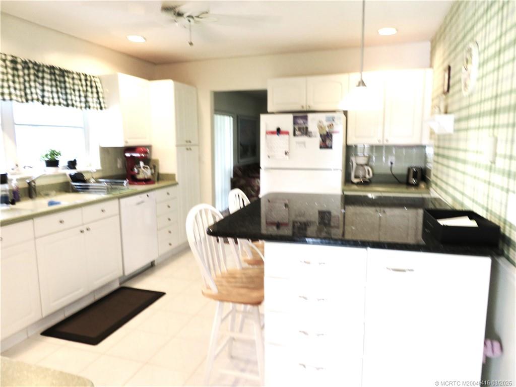 1843 Southeast Granada Lane Stuart, FL 34996 - Photo 16 of 31 a large white kitchen with stainless steel appliances kitchen island granite countertop a sink and cabinets