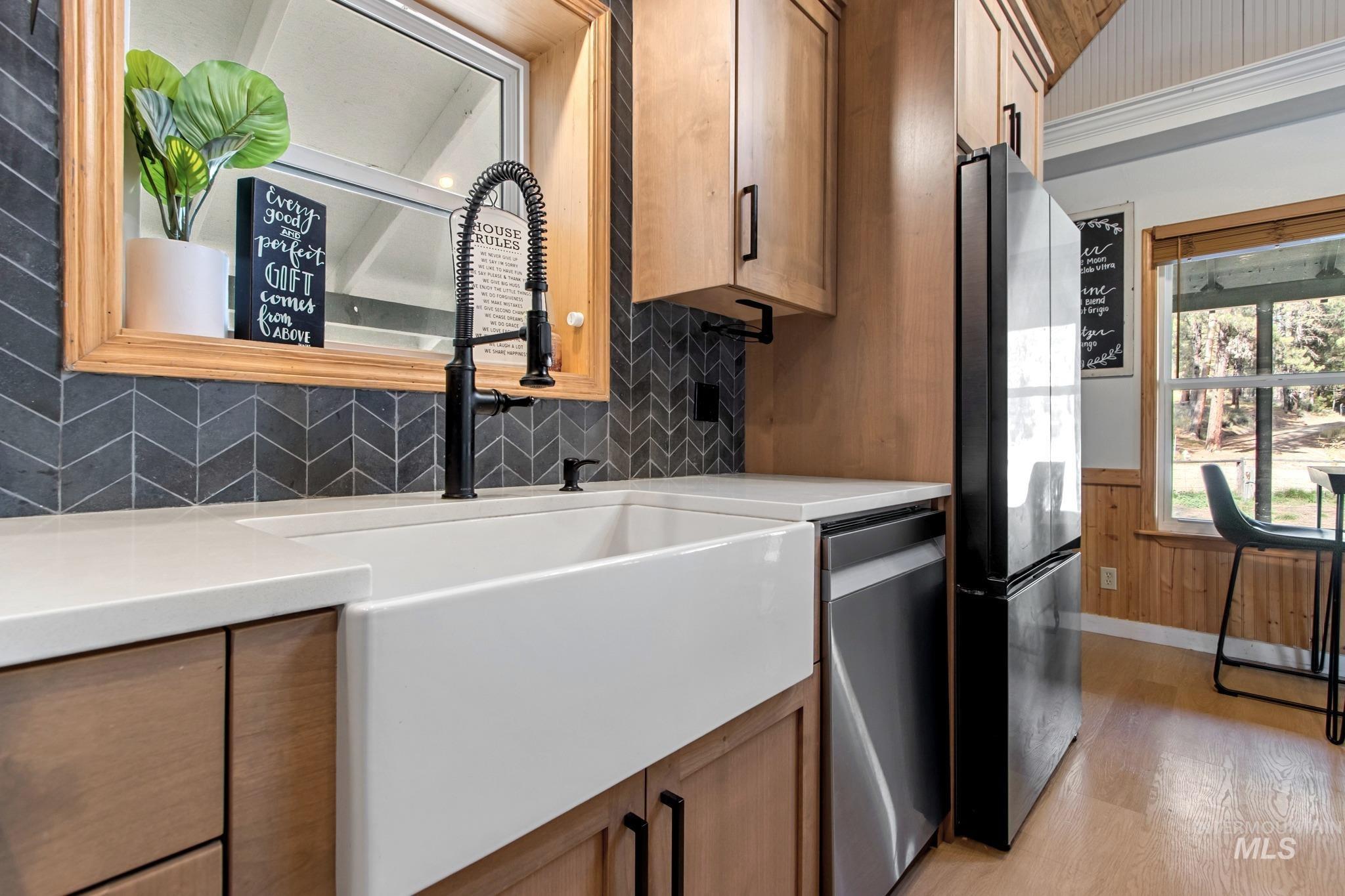12 Meadow Creek Road Idaho City, ID 83631 - Photo 11 of 44 Kitchen with light wood-style floors, freestanding refrigerator, stainless steel dishwasher, wainscoting, and tasteful backsplash