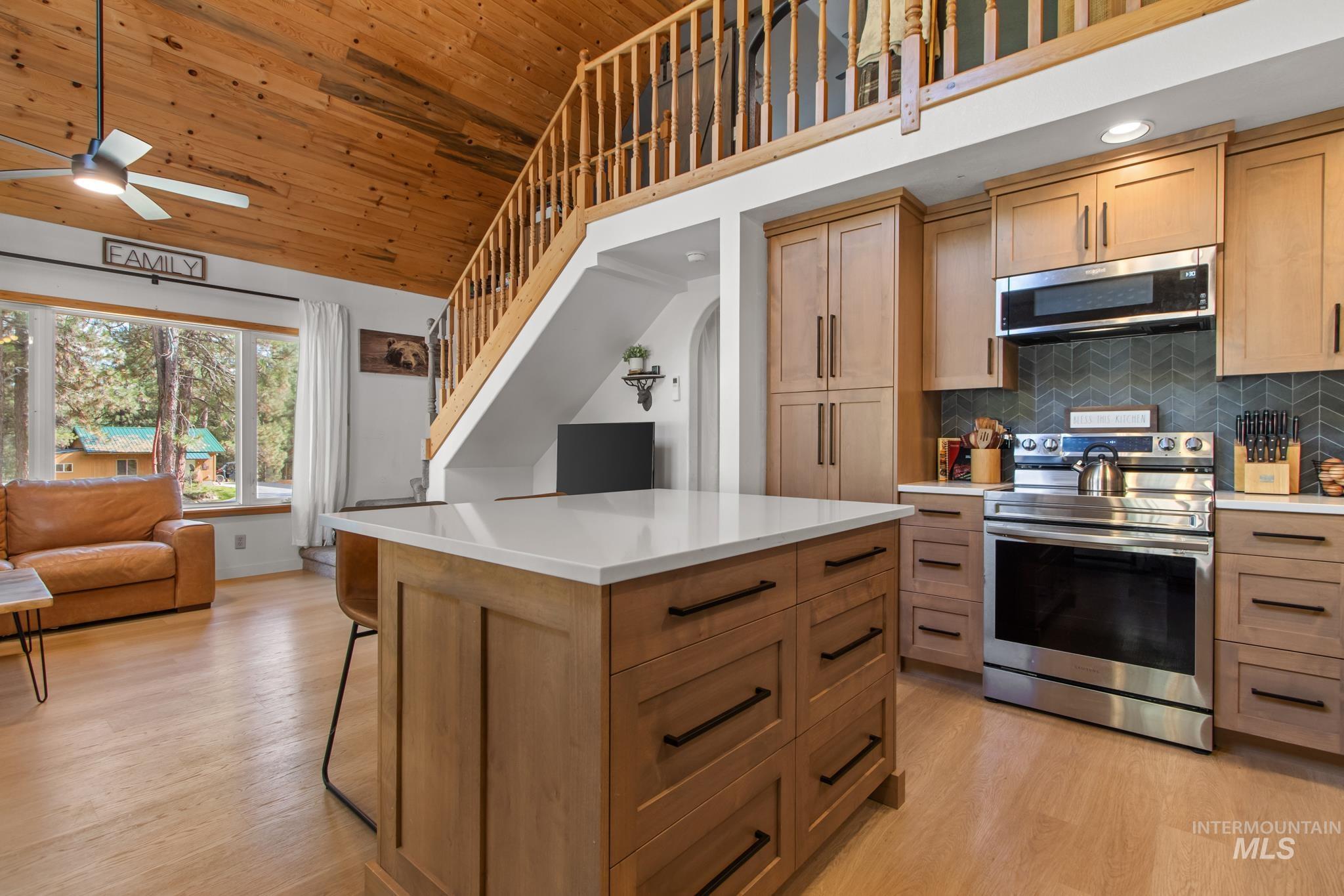 12 Meadow Creek Road Idaho City, ID 83631 - Photo 14 of 44 Kitchen featuring appliances with stainless steel finishes, backsplash, wood ceiling, light wood finished floors, and a center island