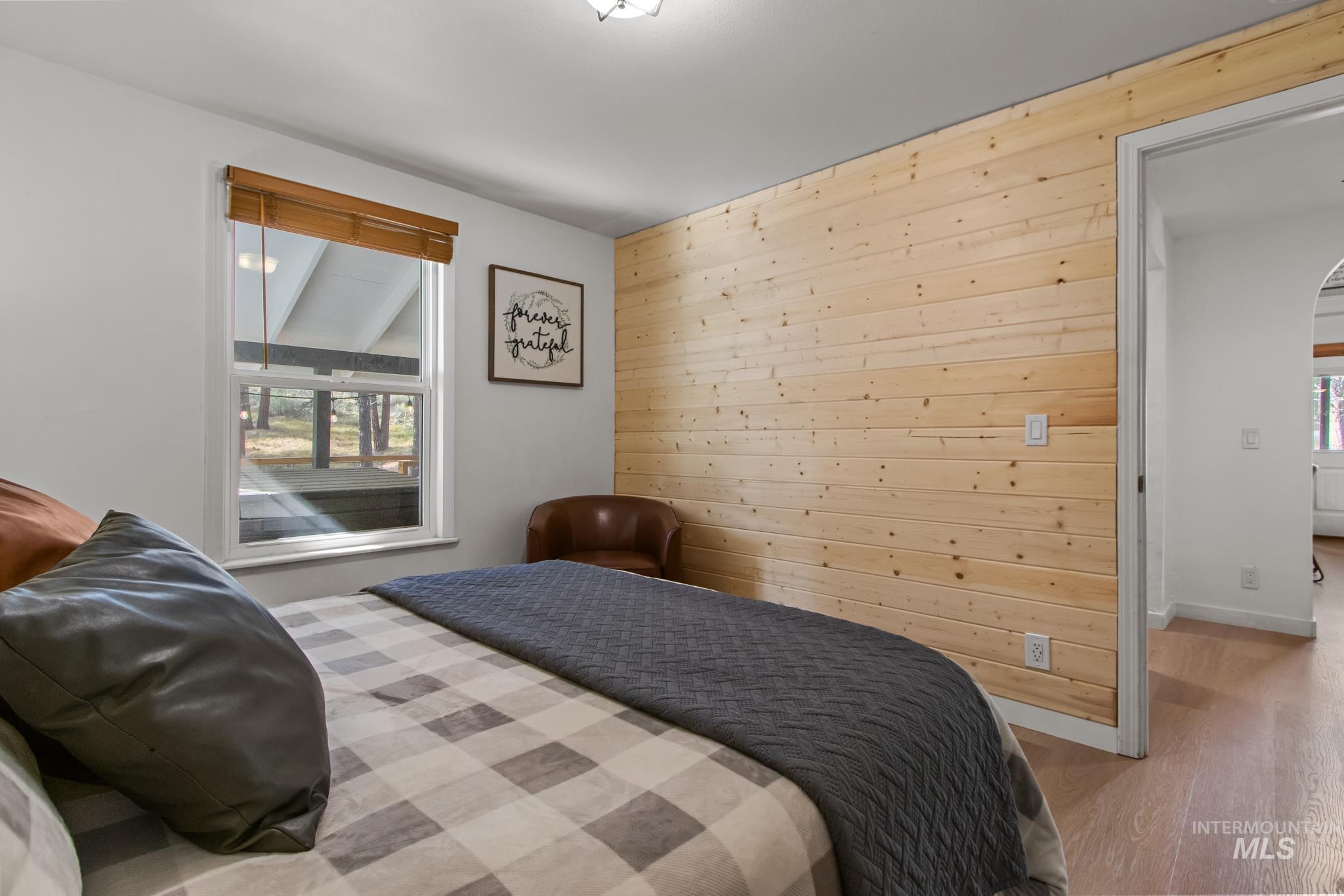12 Meadow Creek Road Idaho City, ID 83631 - Photo 22 of 44 Bedroom featuring wooden walls, wood finished floors, multiple windows, and arched walkways
