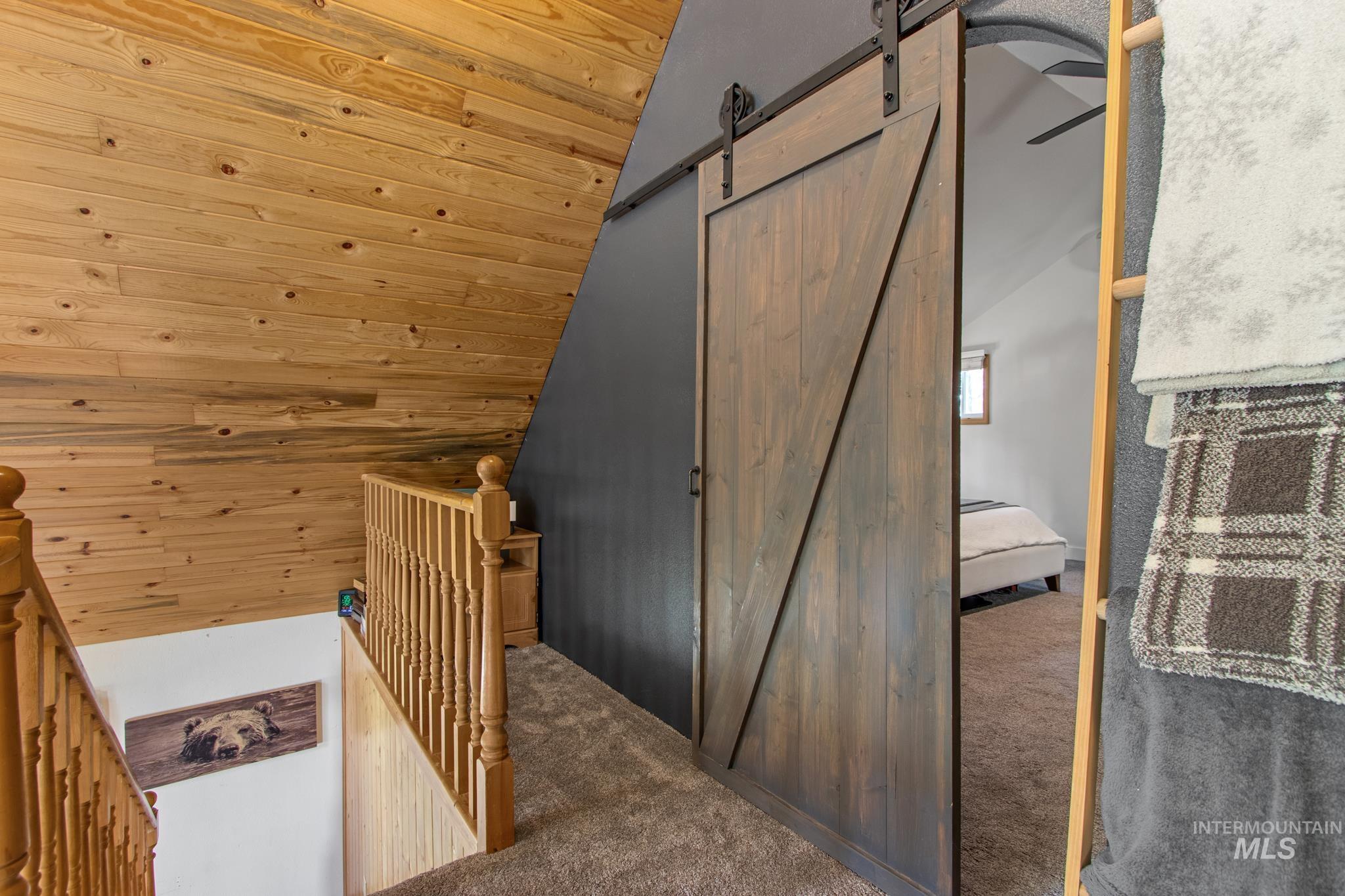 12 Meadow Creek Road Idaho City, ID 83631 - Photo 29 of 44 Stairway featuring a barn door, carpet flooring, lofted ceiling, wood ceiling, and wooden walls