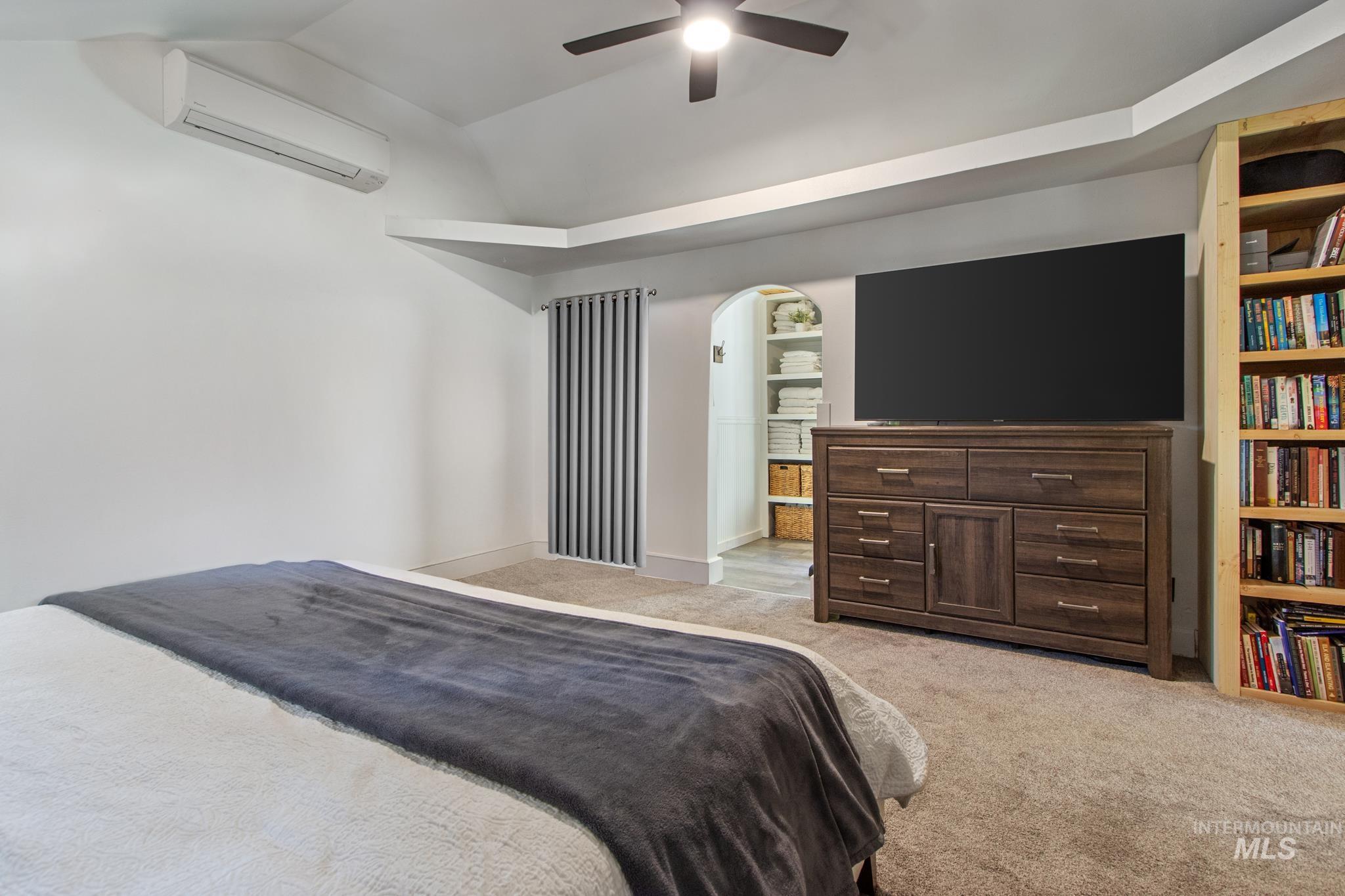 12 Meadow Creek Road Idaho City, ID 83631 - Photo 32 of 44 Bedroom with light carpet, a wall mounted AC, ceiling fan, vaulted ceiling, and arched walkways