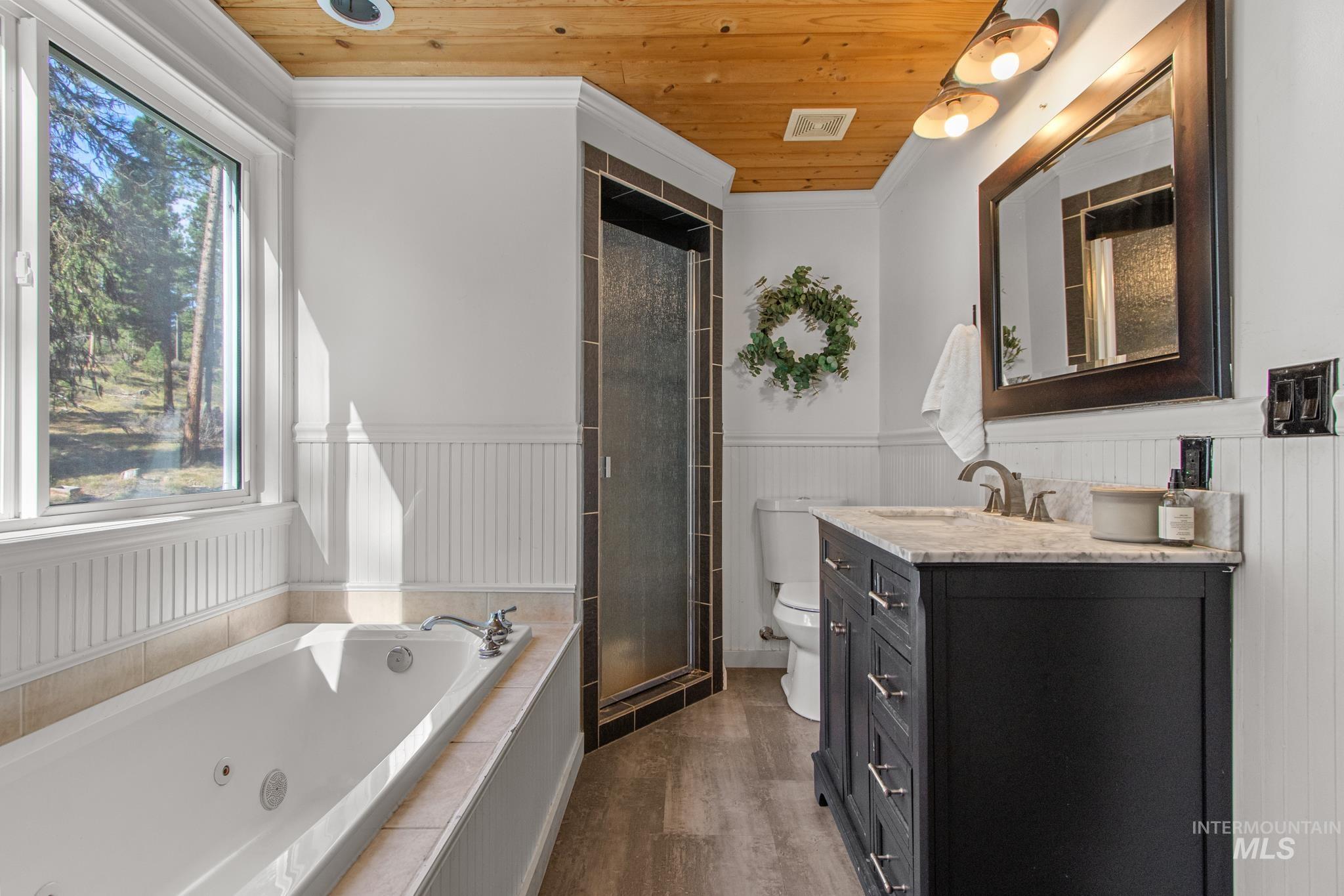 12 Meadow Creek Road Idaho City, ID 83631 - Photo 34 of 44 Full bath with a jetted tub, wood ceiling, crown molding, dark wood-style floors, and vanity