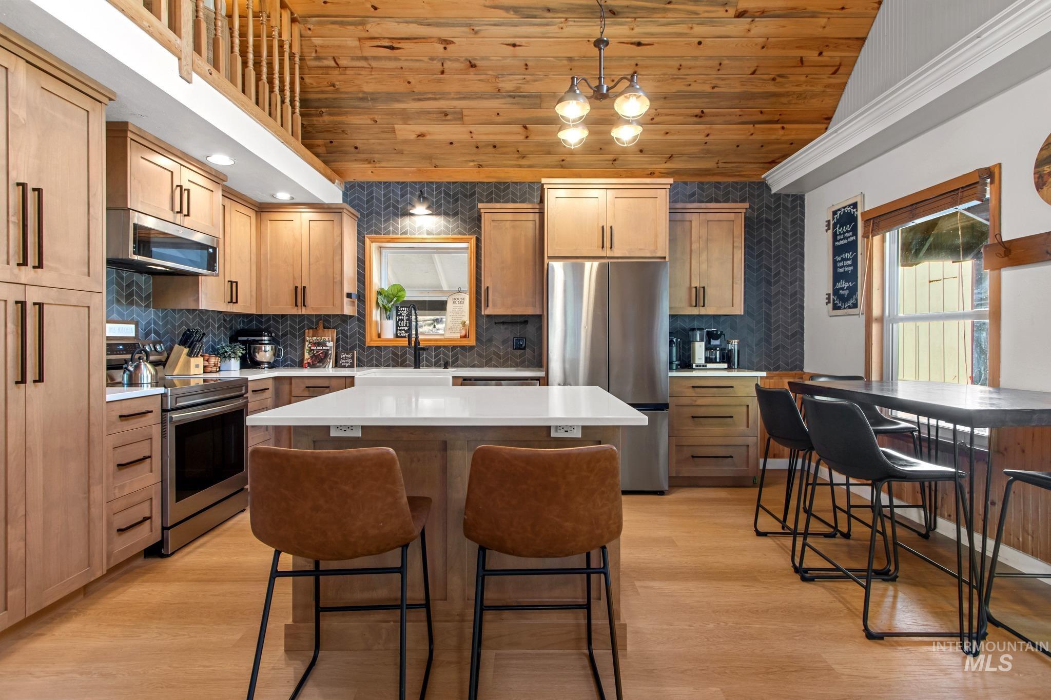 12 Meadow Creek Road Idaho City, ID 83631 - Photo 7 of 44 Kitchen with a kitchen island, appliances with stainless steel finishes, wood ceiling, a breakfast bar, and light wood-style flooring