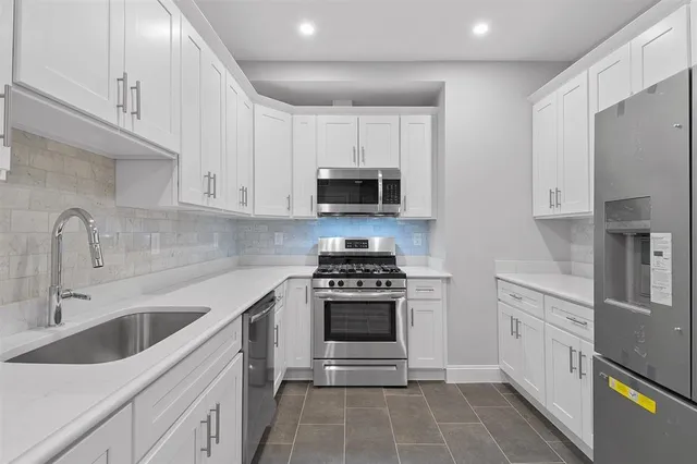 a kitchen with stainless steel appliances granite countertop white cabinets a stove a sink and dishwasher
