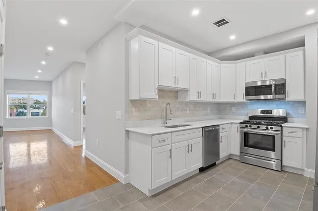 a kitchen with stainless steel appliances granite countertop a stove a sink and a refrigerator