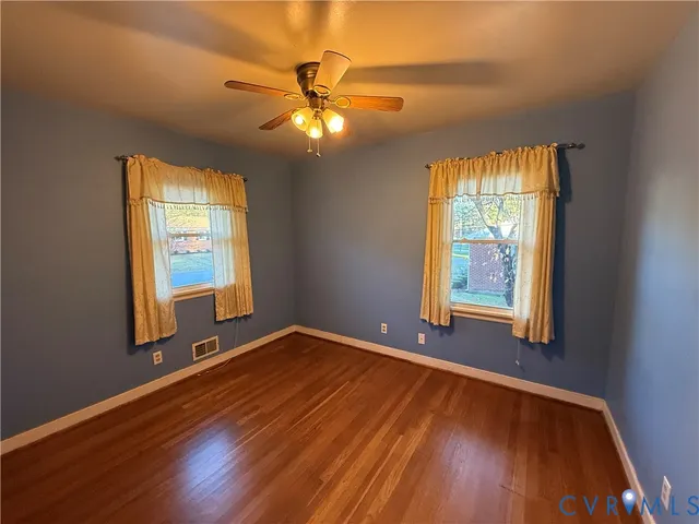 a view of an empty room with window and wooden floor
