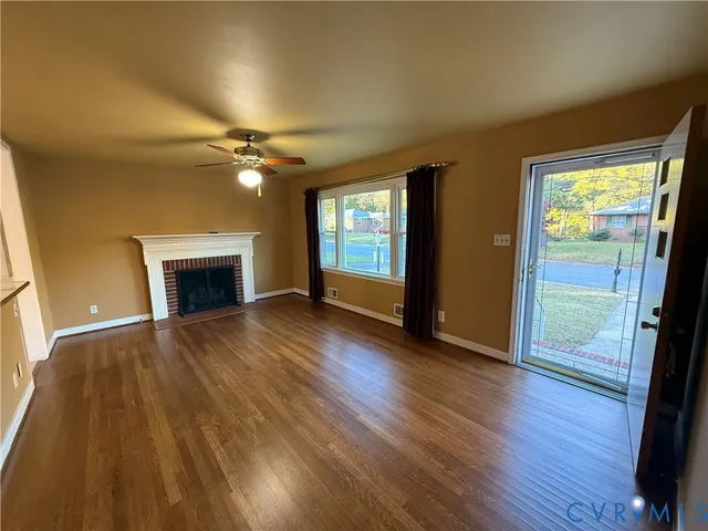 an empty room with wooden floor a fireplace and windows