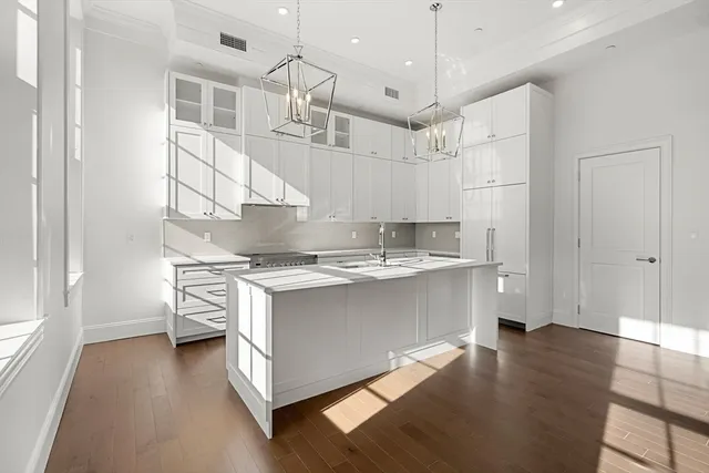 a kitchen with stainless steel appliances granite countertop a sink a stove and a wooden floors