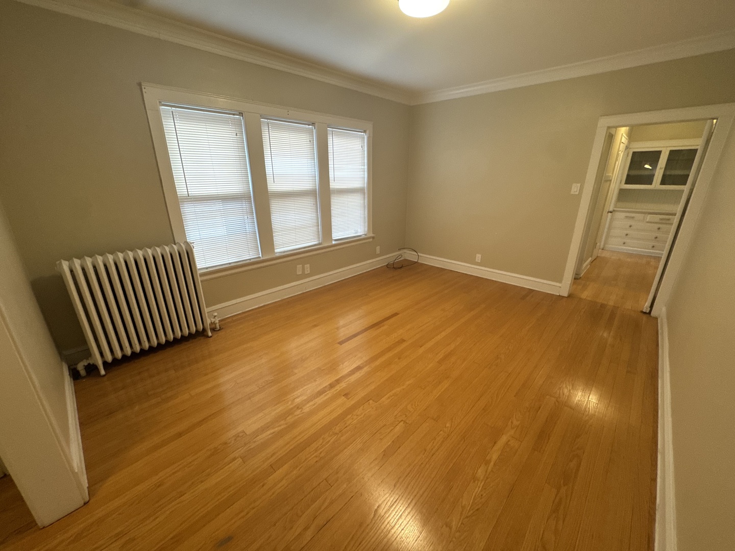6208 North Artesian Avenue, Unit 2 Chicago, IL 60659 - Photo 5 of 14 a view of an empty room with wooden floor and a window