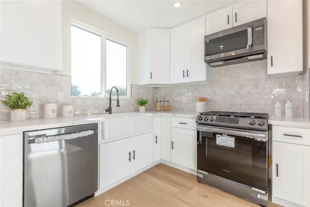 a kitchen with stainless steel appliances white cabinets and a stove top oven
