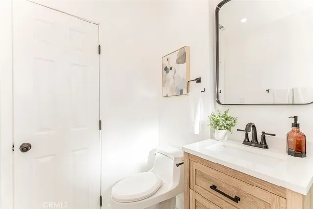 a bathroom with a granite countertop sink and a toilet