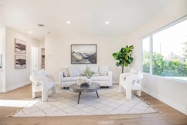 a living room with furniture a potted plant and a large window
