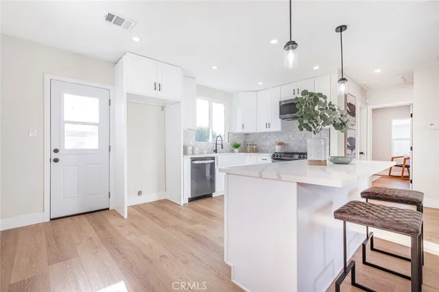 a kitchen with kitchen island white cabinets and stainless steel appliances