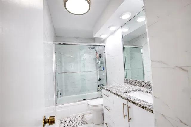 a bathroom with a granite countertop sink a toilet and shower