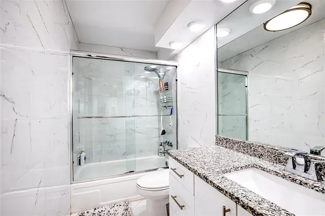 a bathroom with a granite countertop sink toilet mirror and shower