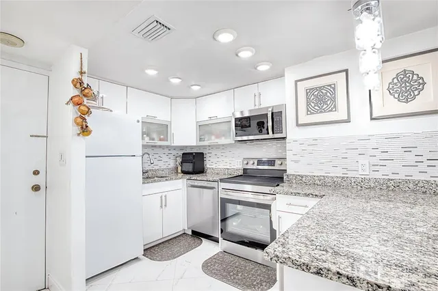 a kitchen with stainless steel appliances granite countertop a refrigerator sink stove and microwave