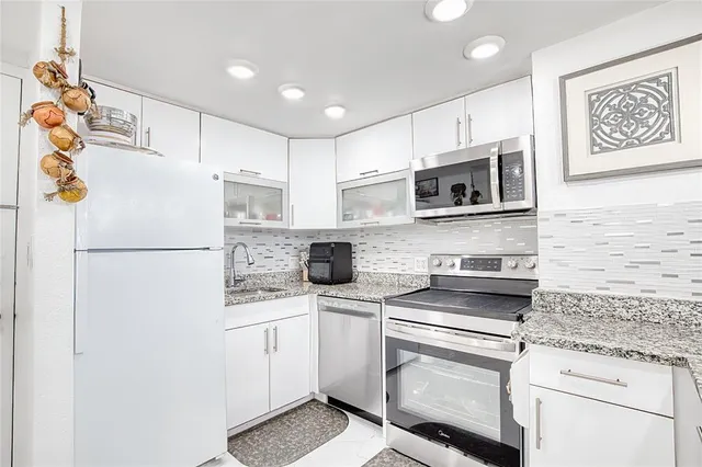 a kitchen with stainless steel appliances granite countertop a refrigerator sink stove microwave and cabinets