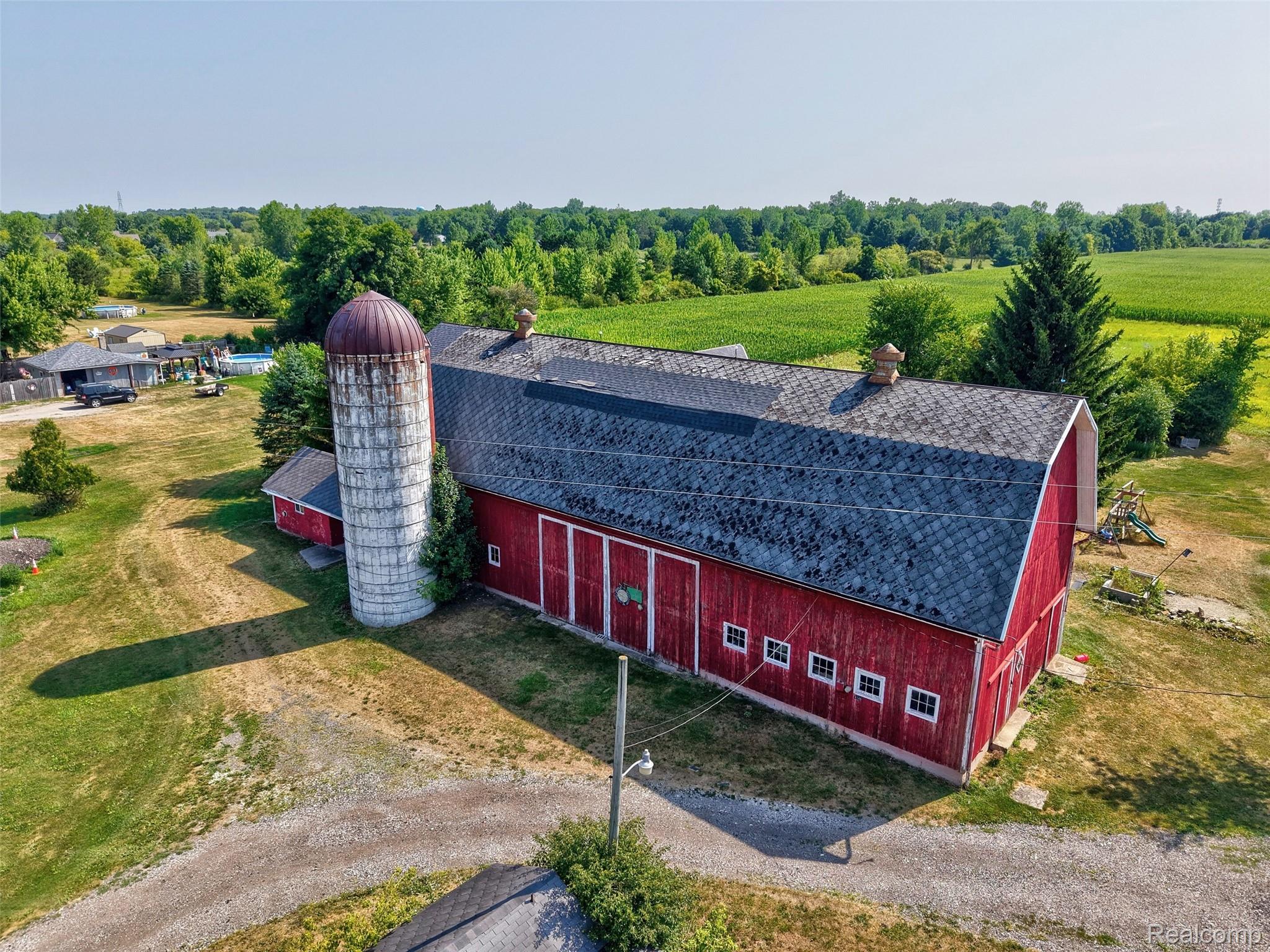 1175 South Morrish Road Flint, MI 48532 - Photo 59 of 72 Large red barn with white trim, featuring multiple entry doors and a shingle roof