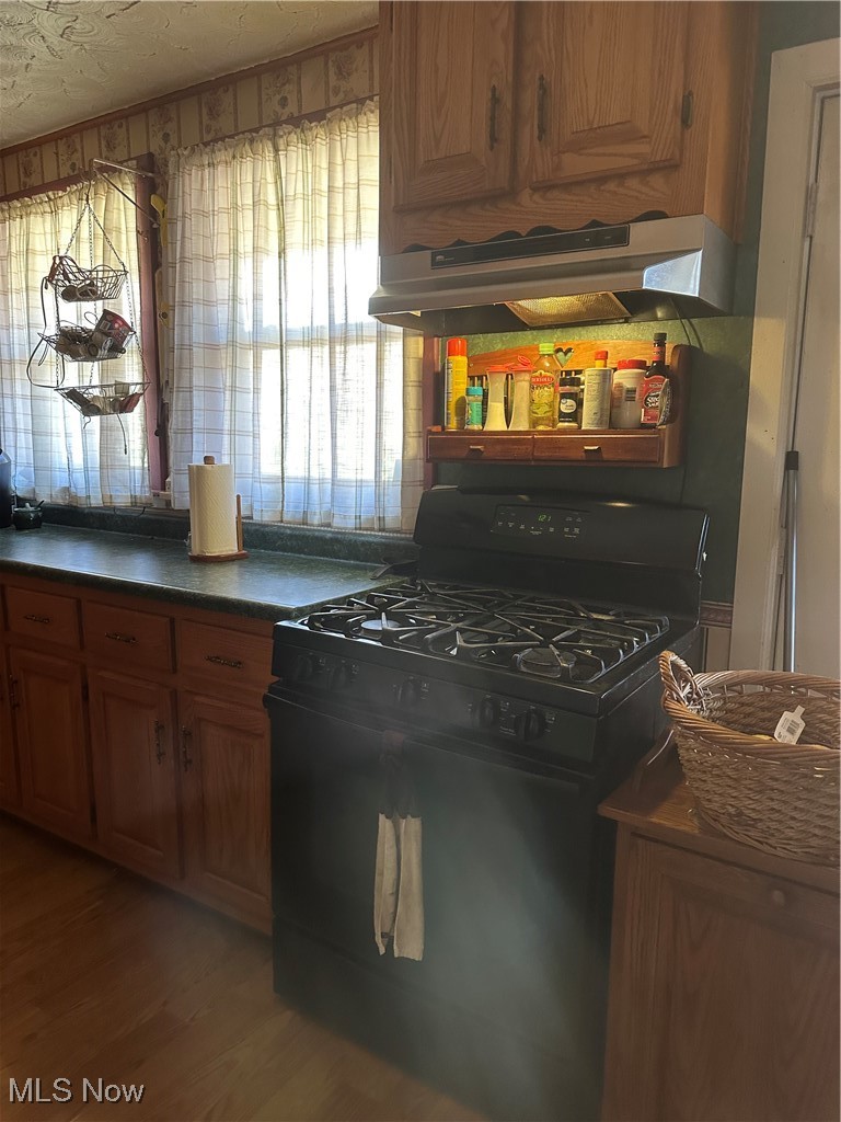 167 Andover Road Woodsfield, OH 43793 - Photo 22 of 50 Kitchen featuring black gas stove, light wood-style floors, range hood, tasteful backsplash, and dark countertops