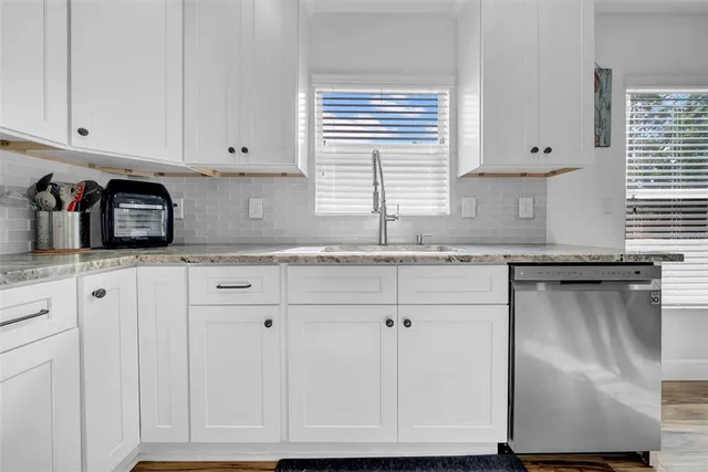 a kitchen with granite countertop white cabinets and a window