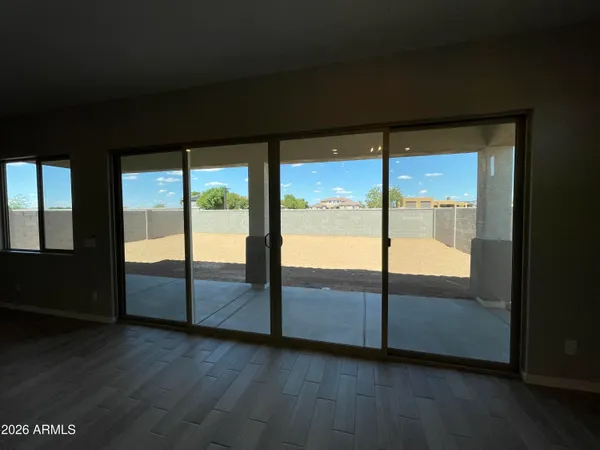 a view of an empty room with wooden floor and windows
