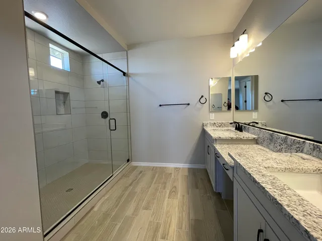 a bathroom with a granite countertop sink a mirror and shower