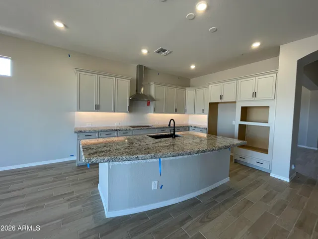 a kitchen with stainless steel appliances granite countertop a sink a refrigerator and a granite counter tops with wooden floors