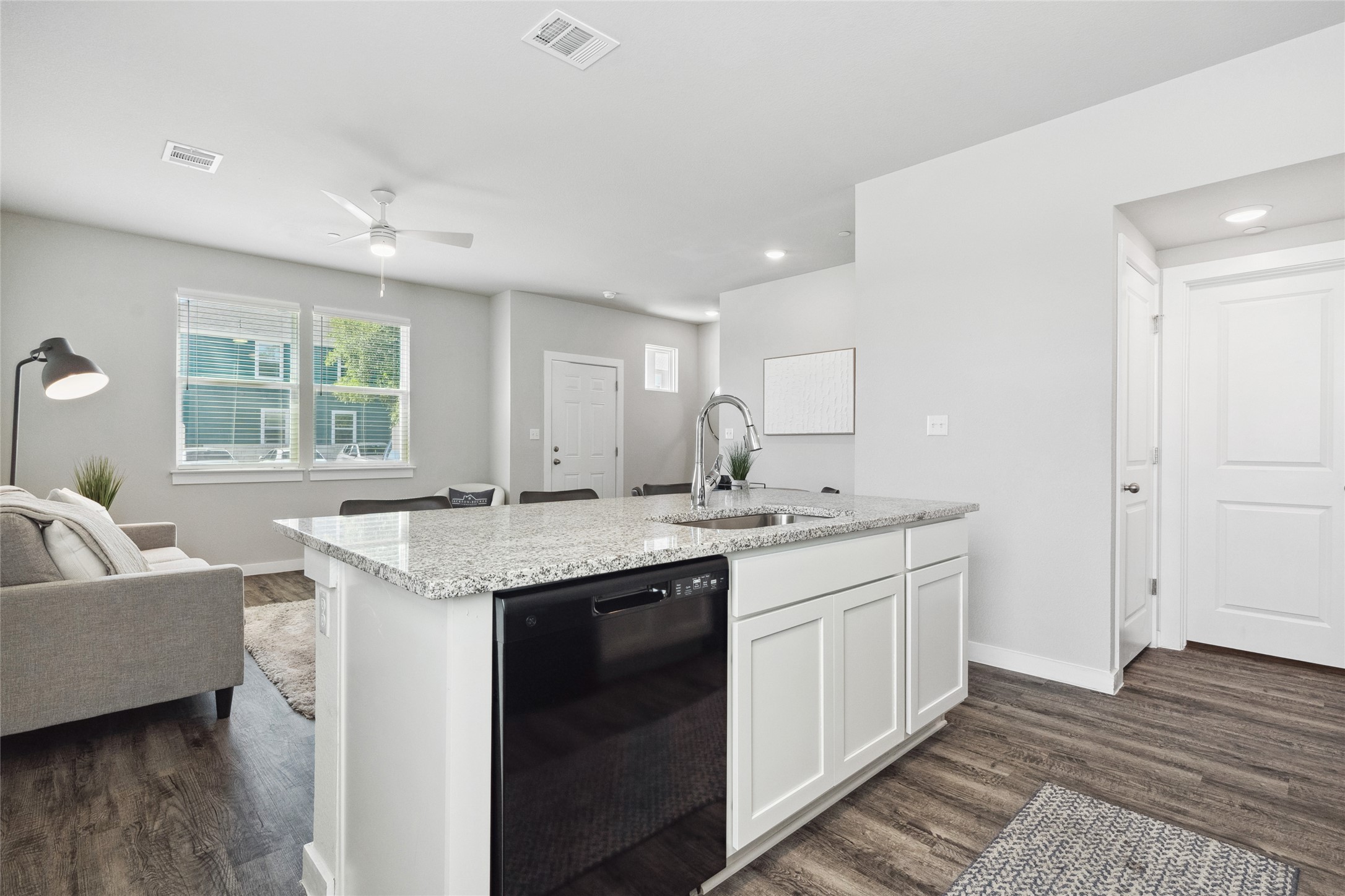 523 Powell Drive, Unit 1101 Leander, TX 78641 - Photo 24 of 24 Kitchen featuring dishwasher, light stone countertops, white cabinetry, open floor plan, and a center island with sink