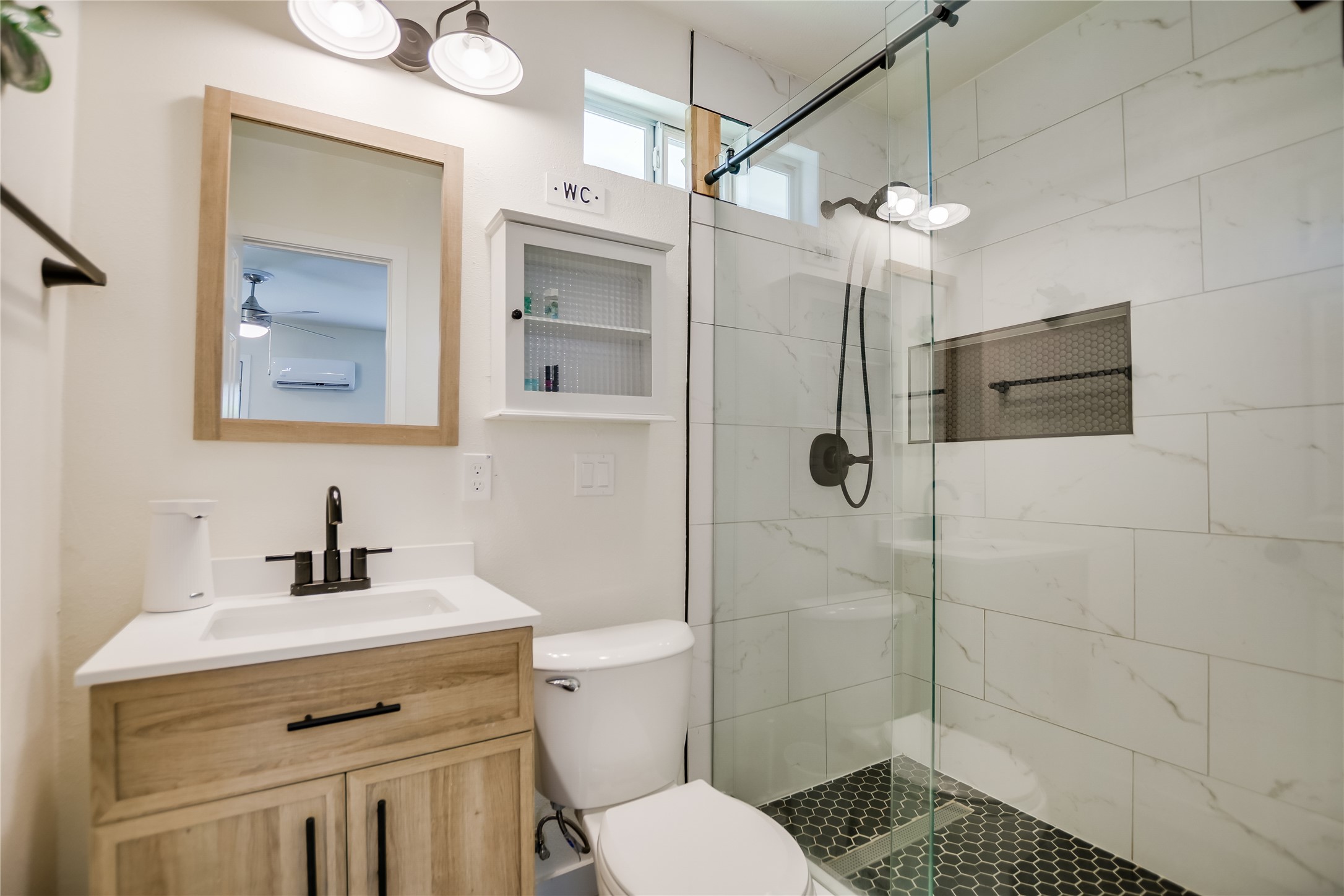 4702 Crest Oak Road Austin, TX 78744 - Photo 20 of 20 Modern bathroom featuring a wood-finish vanity with an integrated sink, quartz countertop, and matte black faucet