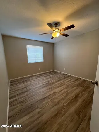a view of an empty room with window and wooden floor