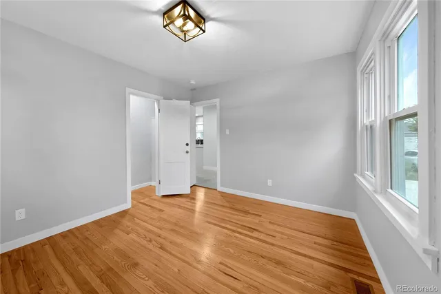 a view of empty room with window and wooden floor