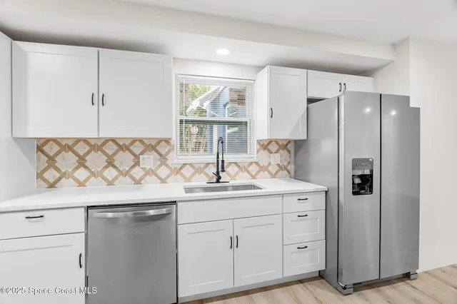a kitchen with white cabinets and a refrigerator