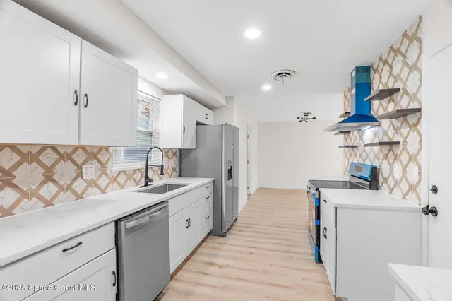 a large white kitchen with a sink a stove a refrigerator and a window