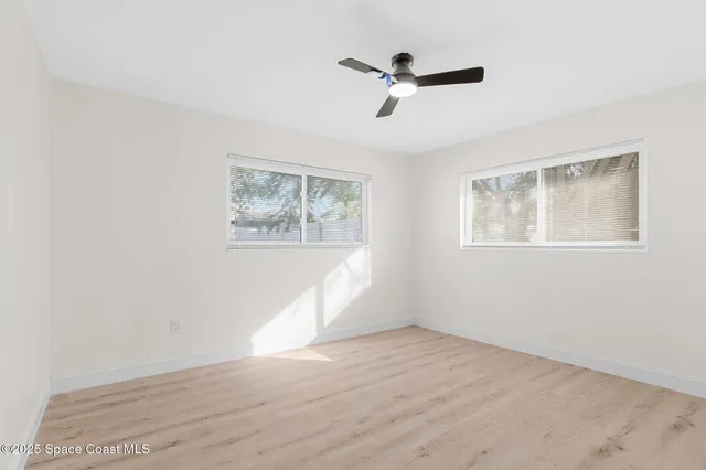 a view of empty room with wooden floor and fan