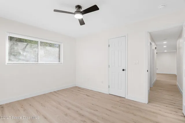 an empty room with wooden floor cabinet and windows