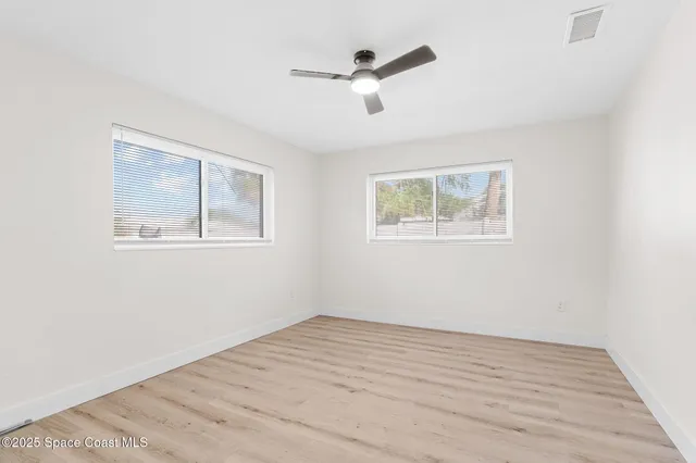 a view of empty room with wooden floor and fan