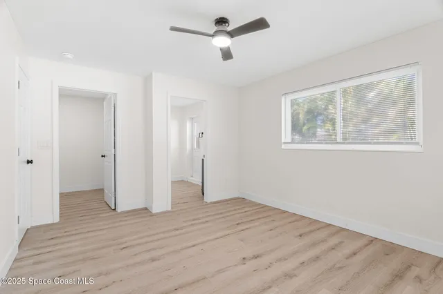 a view of empty room with wooden floor and ceiling fan