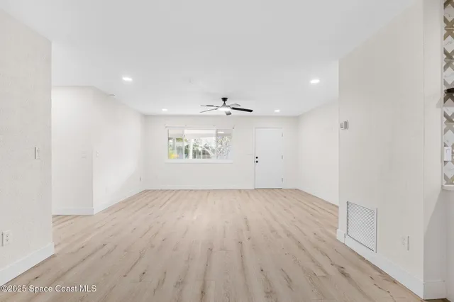 an empty room with wooden floor white walls and windows