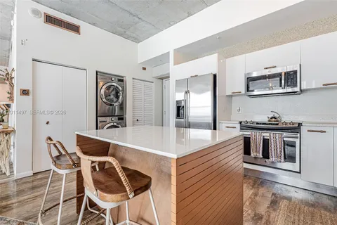 a large kitchen with stainless steel appliances kitchen island granite countertop a table chairs in it and wooden floors