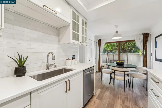 a kitchen with white cabinets a sink and wooden floors