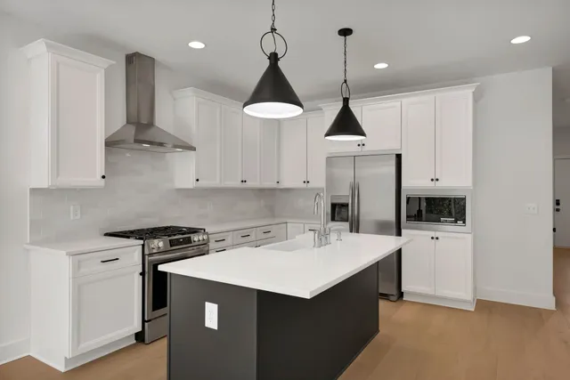 a kitchen with stainless steel appliances a stove a sink and white cabinets