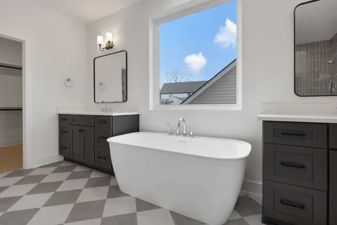 a spacious bathroom with a double vanity sink mirror and bathtub
