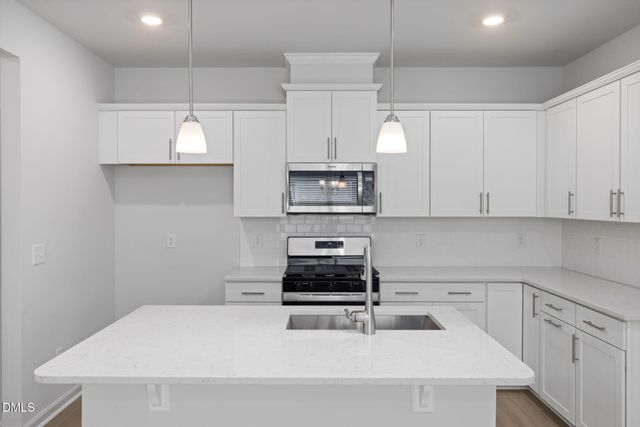 a kitchen with stainless steel appliances granite countertop a refrigerator a stove a sink a dining table and chairs