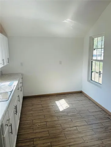 a kitchen with stainless steel appliances granite countertop a stove a sink and white cabinets with wooden floor