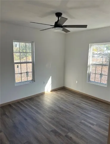 an empty room with wooden floor closet and windows