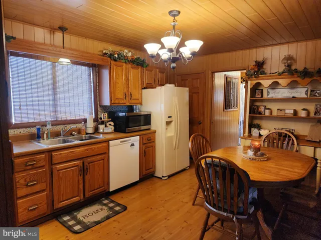 a kitchen with stainless steel appliances granite countertop a dining table chairs sink refrigerator and microwave