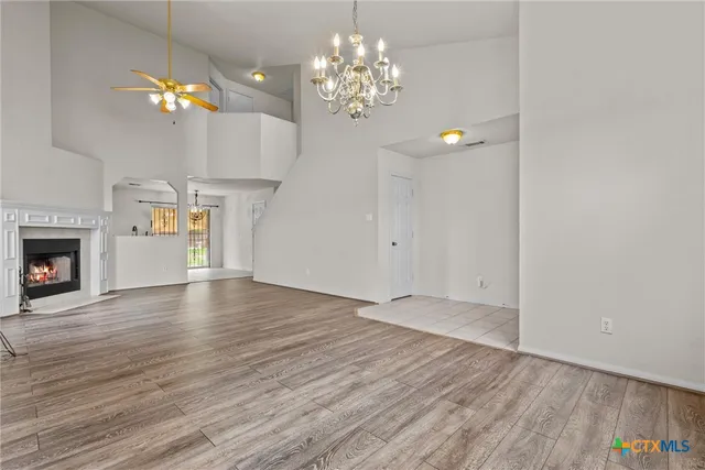 a view of an empty room with chandelier and wooden floor